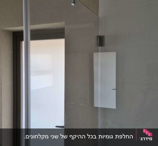 מקלחון זכוכית מותקן בחדר רחצה עם צירי מתכת וגומיות איטום